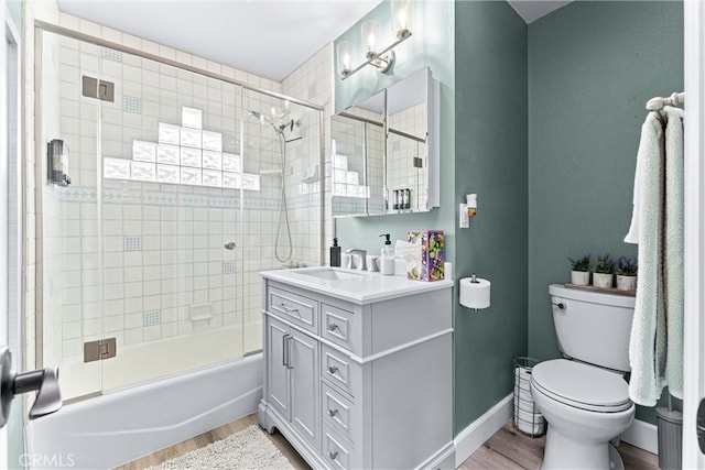 bathroom featuring vanity, toilet, wood finished floors, and baseboards