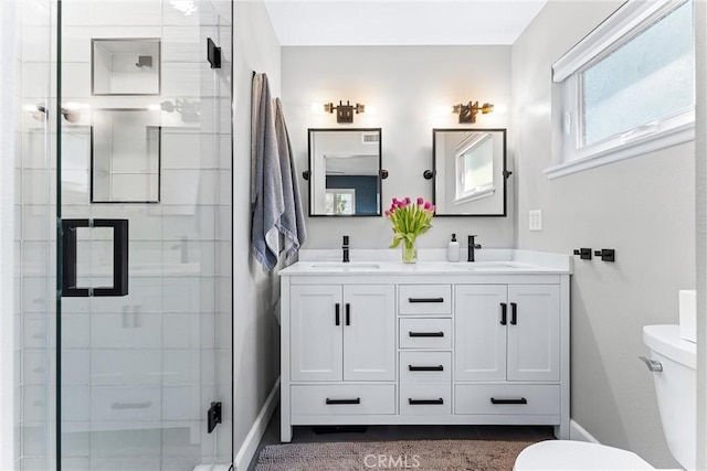 bathroom with a sink, toilet, double vanity, and a shower stall