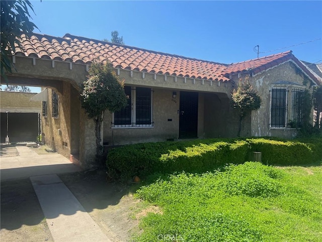 mediterranean / spanish house with stucco siding, driveway, and a tile roof