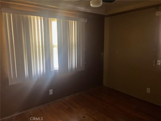 spare room with a wealth of natural light, ceiling fan, and wood finished floors