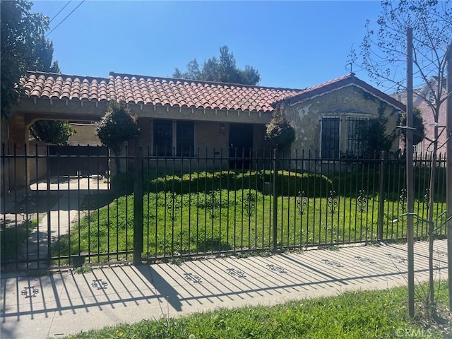 view of front of house with a tile roof, a front yard, a fenced front yard, and stucco siding