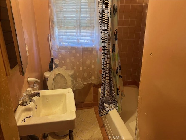 full bath with tile patterned flooring, shower / bath combination with curtain, and a sink