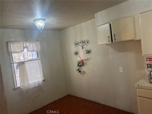 unfurnished room featuring a textured ceiling and a chandelier