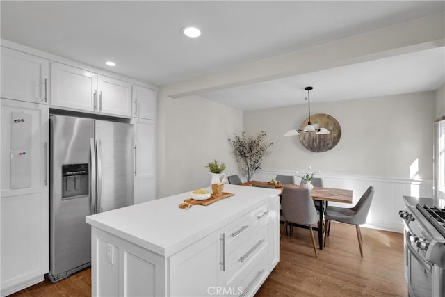 kitchen with dark wood finished floors, white cabinetry, stainless steel appliances, wainscoting, and light countertops