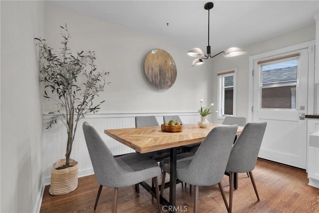 dining area with a wainscoted wall, a notable chandelier, and wood finished floors