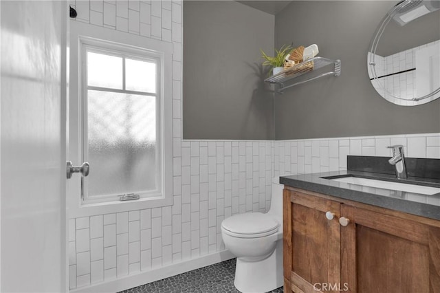 bathroom with vanity, tile walls, toilet, and a wainscoted wall