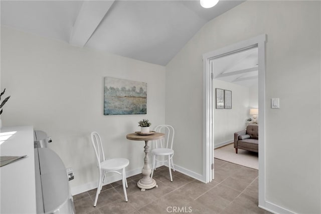 dining space featuring light tile patterned flooring, baseboards, and lofted ceiling