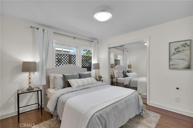 bedroom with wood finished floors, baseboards, and a closet