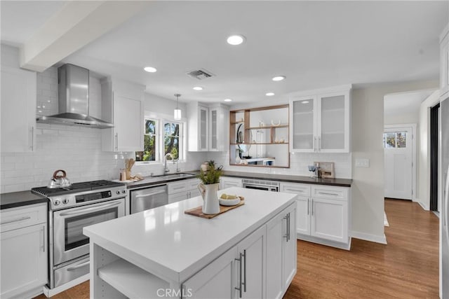 kitchen with open shelves, a sink, white cabinets, appliances with stainless steel finishes, and wall chimney range hood