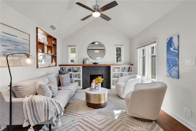 living area featuring visible vents, baseboards, a fireplace, wood finished floors, and a ceiling fan