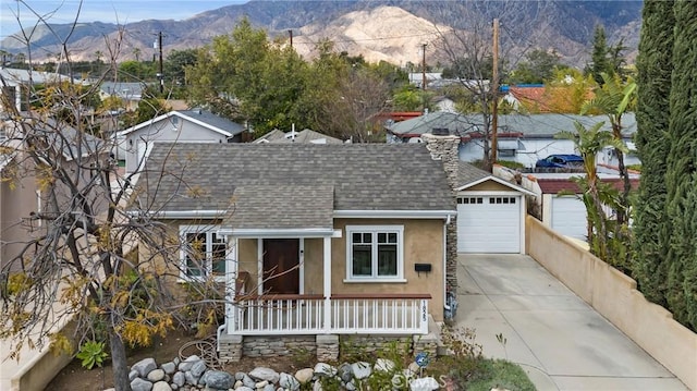 view of front facade with stucco siding, a mountain view, roof with shingles, concrete driveway, and a garage