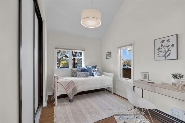 bedroom with baseboards, high vaulted ceiling, and wood finished floors