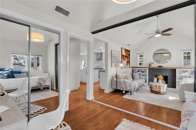 living room featuring wood finished floors, a ceiling fan, visible vents, and lofted ceiling