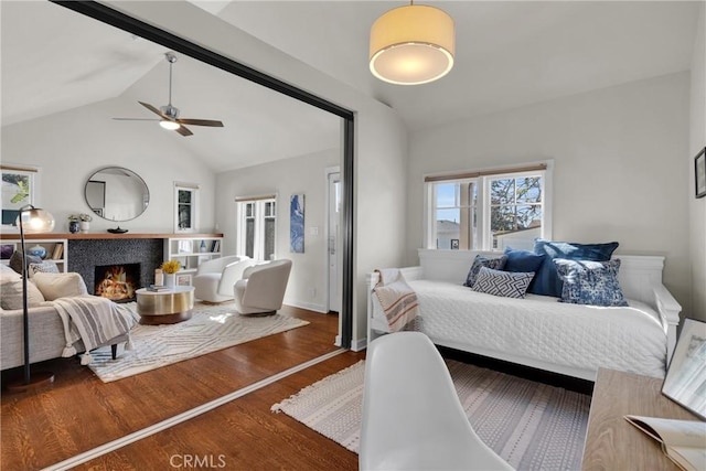 bedroom with high vaulted ceiling, a ceiling fan, wood finished floors, a fireplace, and baseboards