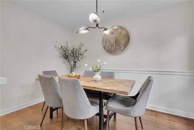 dining area featuring a wainscoted wall, baseboards, and wood finished floors