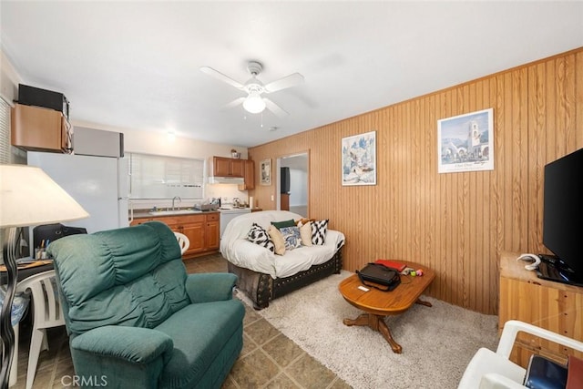 living area with ceiling fan and wood walls