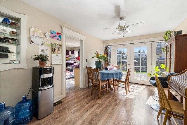 dining space with a ceiling fan, wood finished floors, and french doors