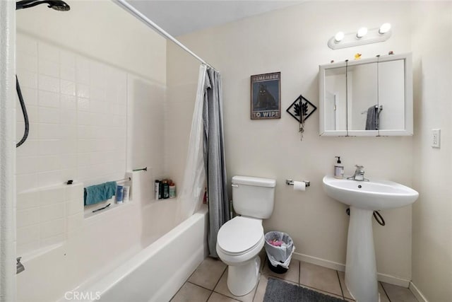 bathroom with baseboards, shower / bath combo, a sink, tile patterned flooring, and toilet