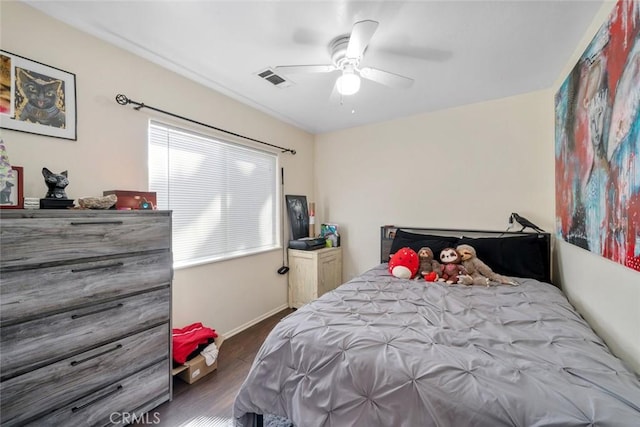 bedroom featuring baseboards, wood finished floors, visible vents, and ceiling fan