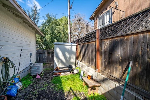 view of yard featuring an outbuilding, central air condition unit, a storage unit, and a fenced backyard