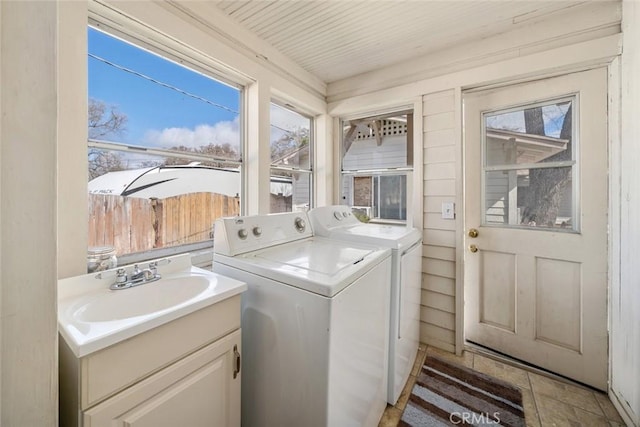 laundry area with laundry area, washer and dryer, a healthy amount of sunlight, and a sink