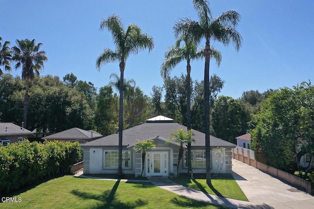 ranch-style home featuring french doors, concrete driveway, a front yard, and fence