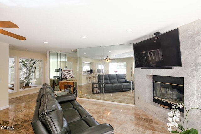 living area featuring recessed lighting, a fireplace, baseboards, and a ceiling fan