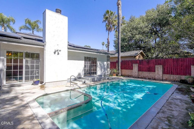 view of swimming pool featuring a pool with connected hot tub, a patio, and fence