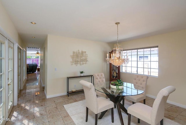 dining area featuring a notable chandelier, a healthy amount of sunlight, and baseboards