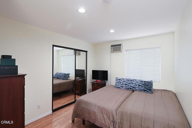 bedroom with recessed lighting, baseboards, light wood finished floors, and a wall mounted AC