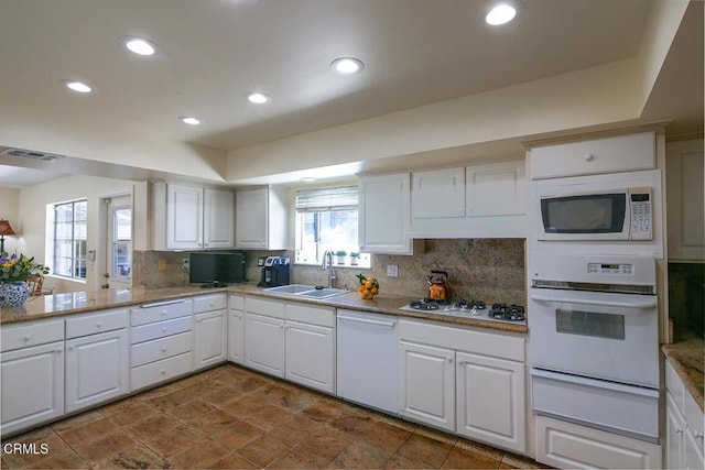 kitchen featuring a warming drawer, a sink, white appliances, white cabinets, and decorative backsplash