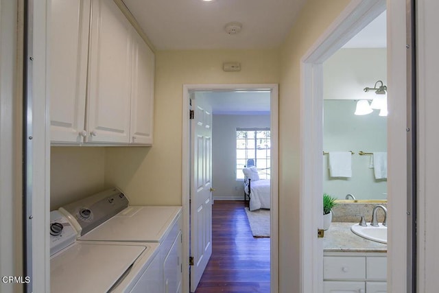 clothes washing area with dark wood-type flooring, independent washer and dryer, a sink, cabinet space, and baseboards