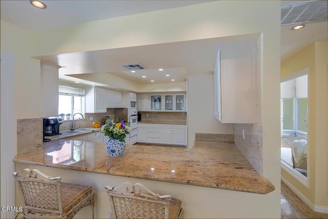 kitchen featuring light stone countertops, visible vents, and a sink