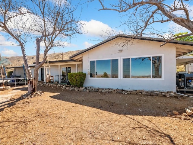 rear view of property featuring stucco siding and a trampoline