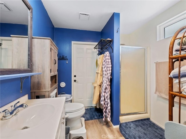 bathroom with vanity, wood finished floors, visible vents, a shower stall, and toilet