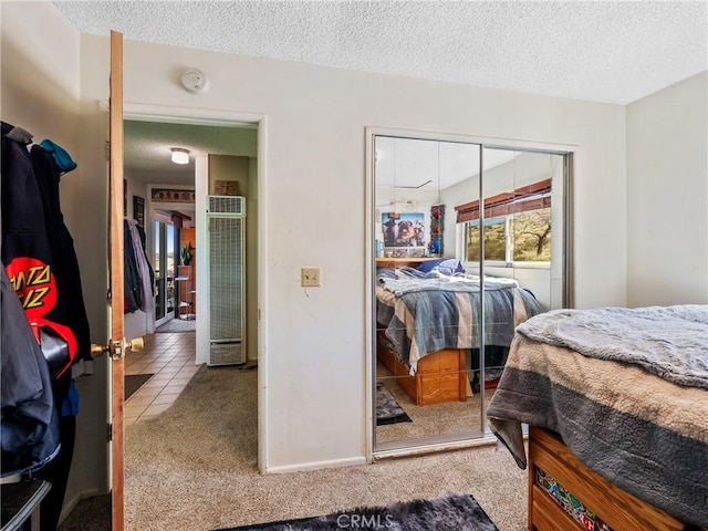 carpeted bedroom featuring a closet, tile patterned flooring, a textured ceiling, and baseboards