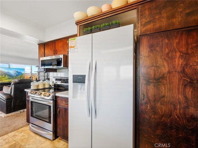 kitchen with open floor plan, light colored carpet, light countertops, light tile patterned floors, and stainless steel appliances