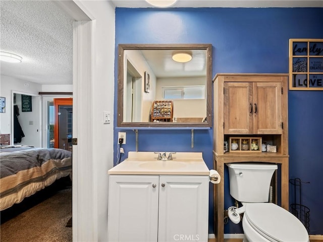 bathroom with a textured ceiling, vanity, and toilet