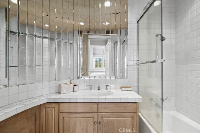 bathroom featuring shower / bath combination with glass door and vanity