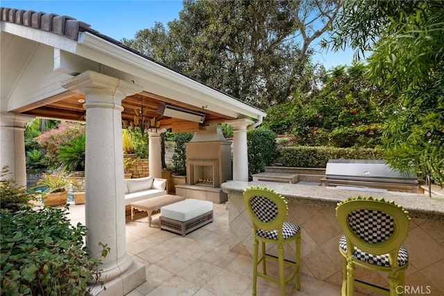 view of patio / terrace featuring a gazebo, area for grilling, and a warm lit fireplace