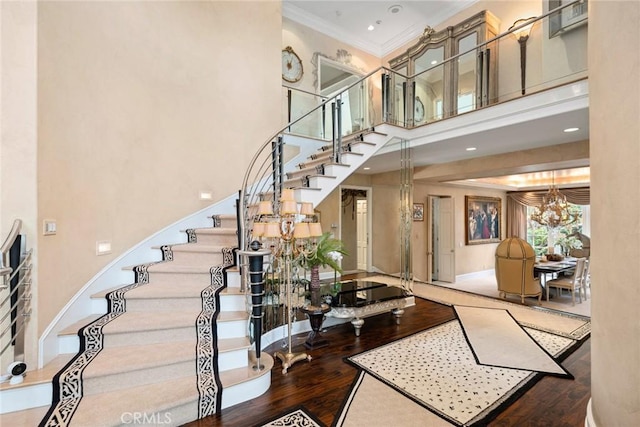 interior space with baseboards, wood finished floors, a towering ceiling, and ornamental molding