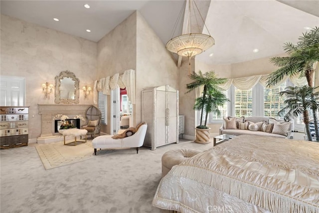 carpeted bedroom featuring recessed lighting, baseboards, a high ceiling, and a lit fireplace