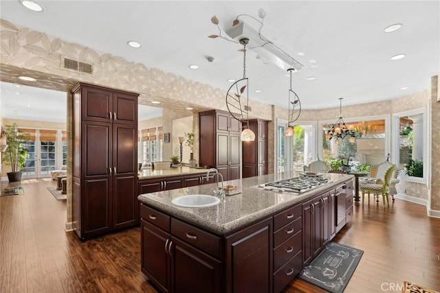 kitchen featuring stainless steel gas cooktop, visible vents, wallpapered walls, and a sink