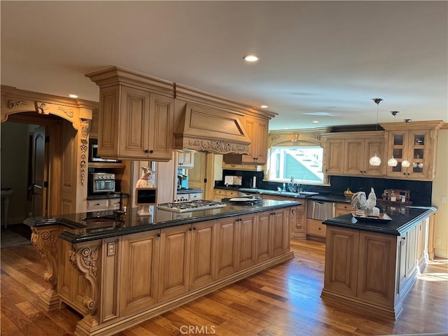 kitchen featuring stainless steel gas cooktop, light wood-style flooring, a center island, and custom range hood