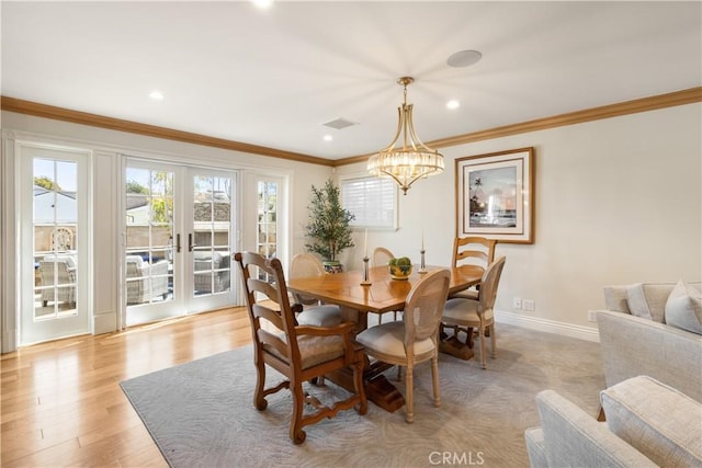 dining room with baseboards, ornamental molding, french doors, light wood-style floors, and a notable chandelier