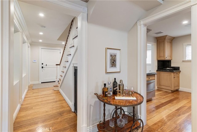 hallway with light wood finished floors, visible vents, baseboards, stairs, and recessed lighting