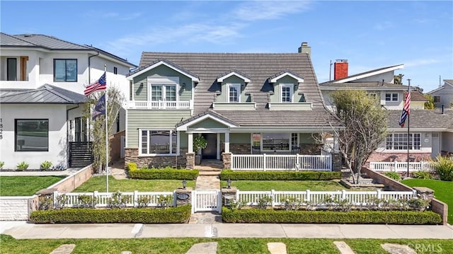 view of front facade featuring a fenced front yard, stone siding, covered porch, and a front yard