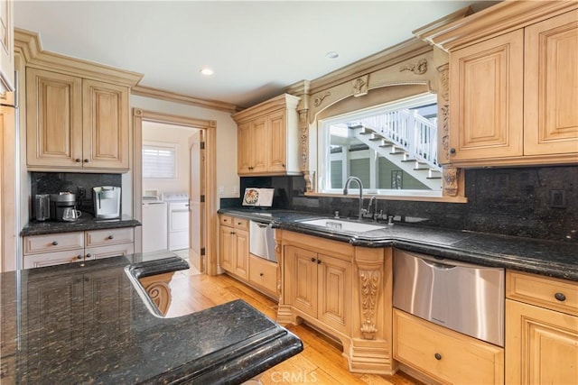 kitchen featuring light wood finished floors, washing machine and clothes dryer, a sink, dishwasher, and tasteful backsplash