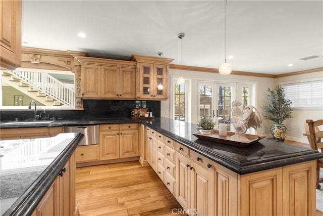 kitchen with a sink, a healthy amount of sunlight, crown molding, light wood-style floors, and stainless steel dishwasher