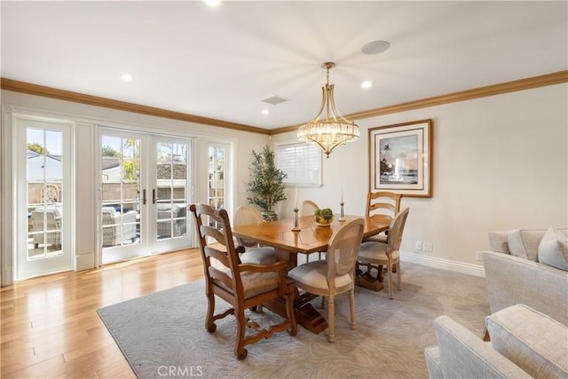 dining space with light wood finished floors, baseboards, ornamental molding, french doors, and a notable chandelier